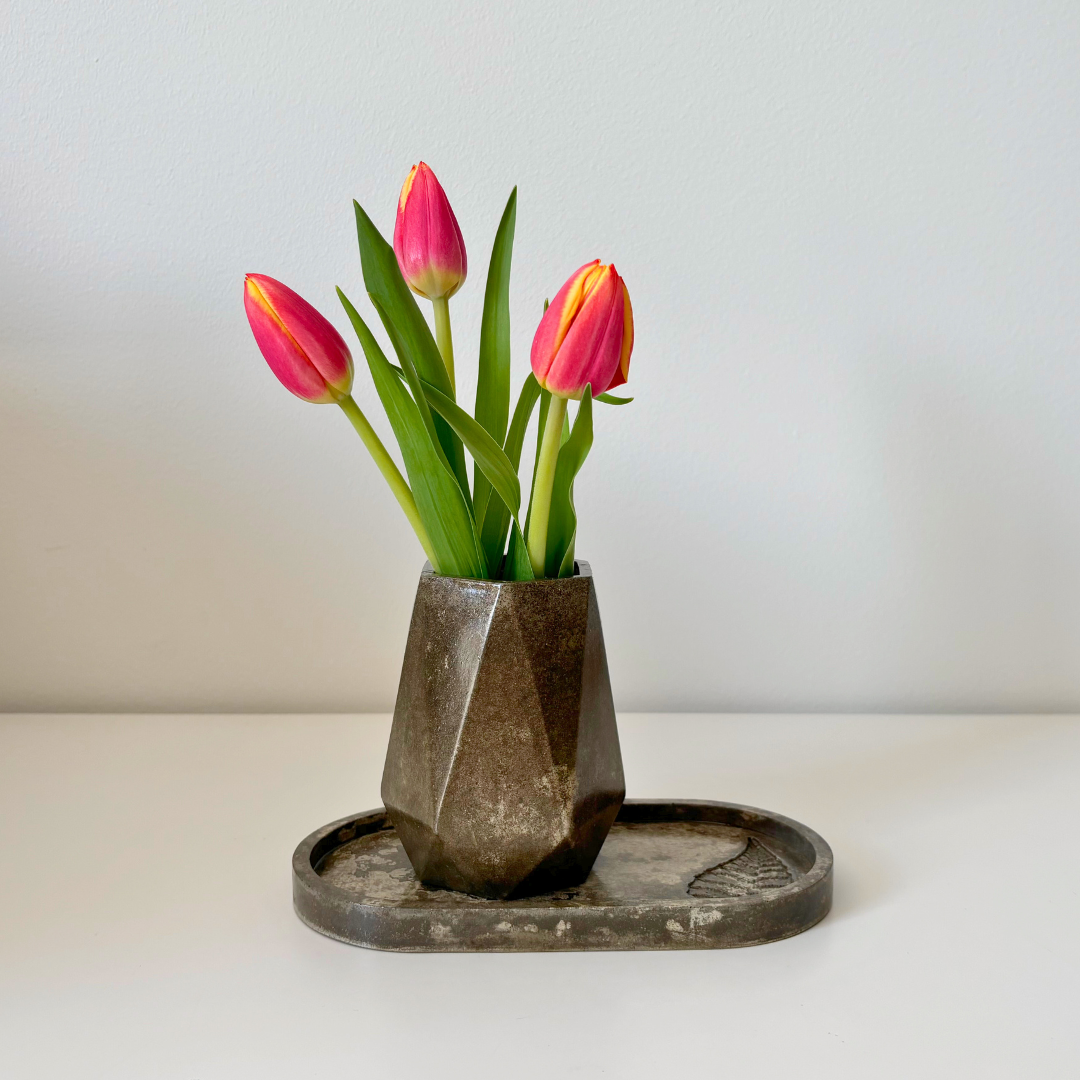 Tulips in a concrete geometric vase, sitting on a conrete oval tray